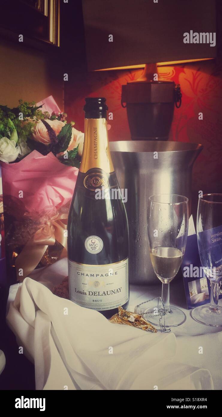 Bottiglia di Champagne, bicchieri e un mazzo di fiori in una camera di hotel Foto Stock