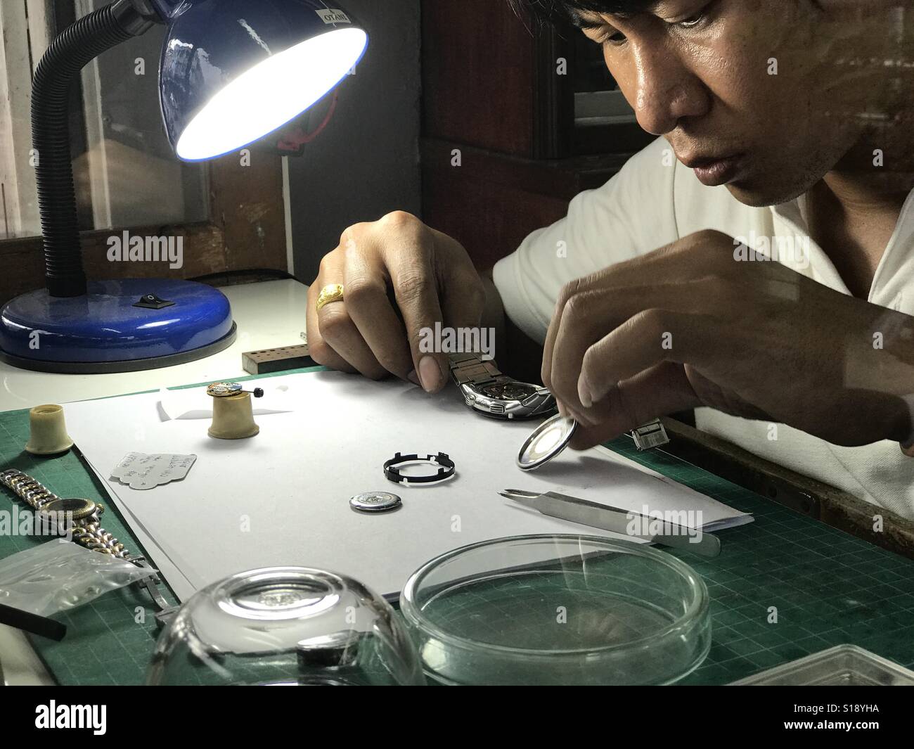 Orologiaio lavorando nel suo negozio riparazione di un orologio Foto Stock