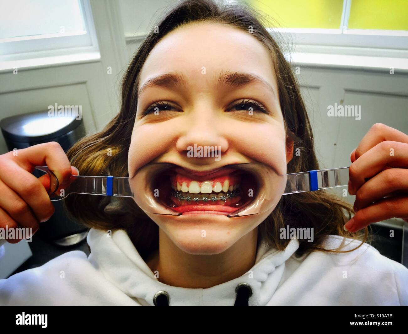 Una ragazza adolescente utilizza strumenti di plastica per visualizzare i suoi denti durante una visita all'ortodontista Gennaio 2017. Foto Stock