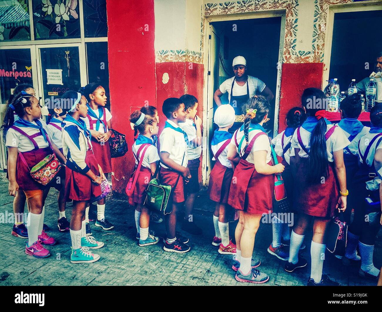 Studenti cubani in uniformi di scuola in attesa in una coda per il cibo di strada Foto Stock