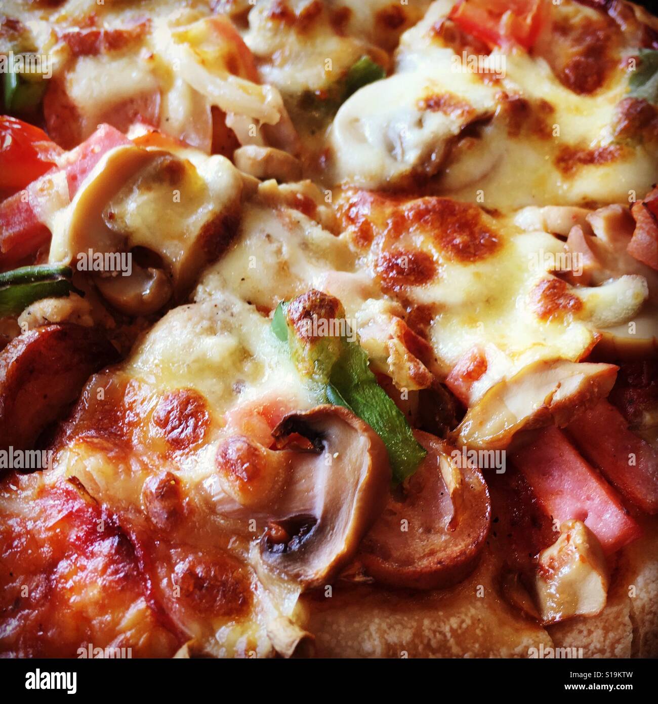 Close up di pizza con formaggio, funghi, peperoni, pollo e hotdog Foto Stock