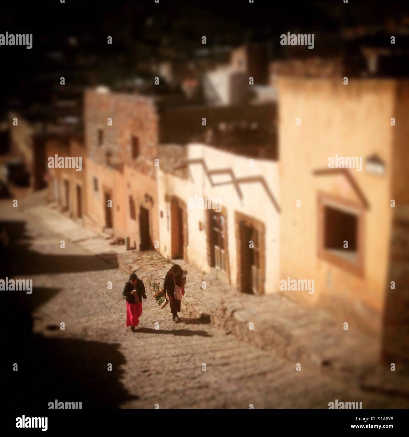 Le donne a piedi passato case alla piazza principale in Real de Catorce, San Luis Potosi, Messico. Foto Stock