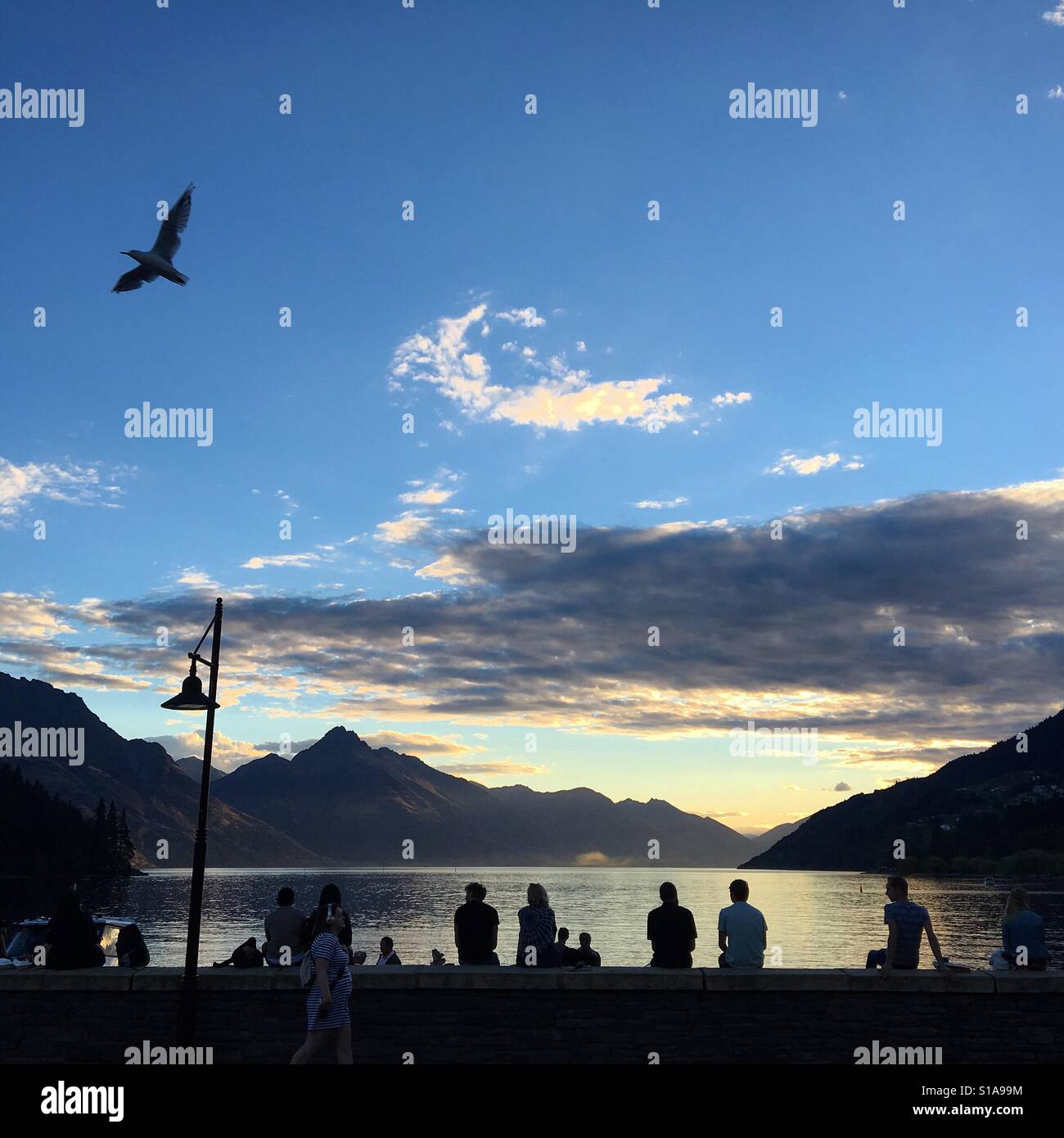 Queenstown in Nuova Zelanda al tramonto con i turisti che guardano il mare Foto Stock