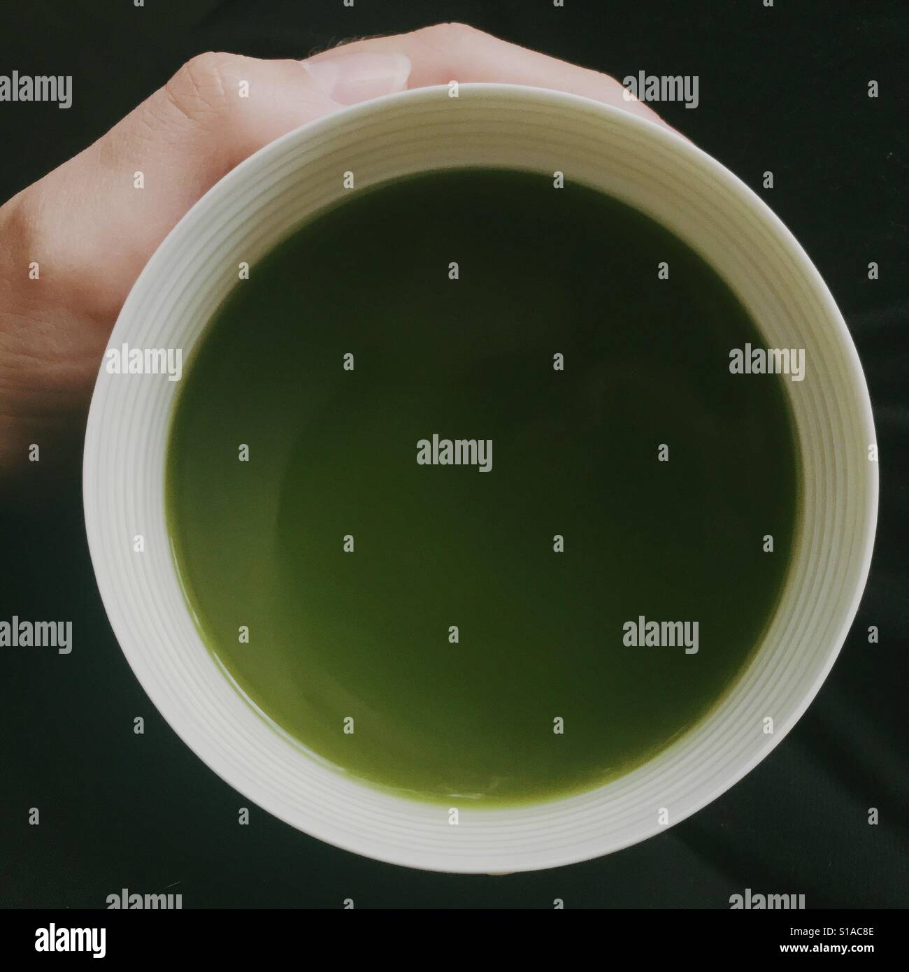 Persona che tiene il tè verde Matcha drink in porcellana bianca ciotola shot dal di sopra Foto Stock