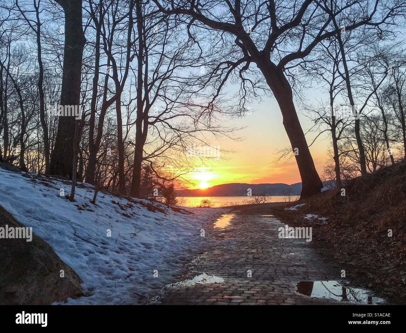 Di un bel colore rosa giallo viola arancione tramonto in inverno nella Valle del fiume Hudson si riflette nelle pozzanghere colorate di fusione della neve. Foto Stock