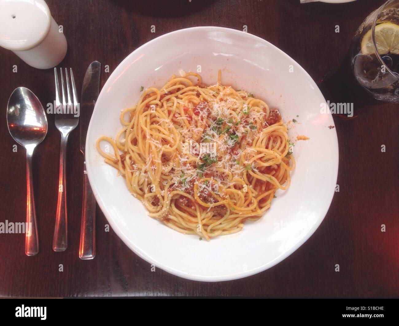 Una ciotola di spaghetti bolognese su un tavolo, visto da sopra con posate sul lato. Foto Stock