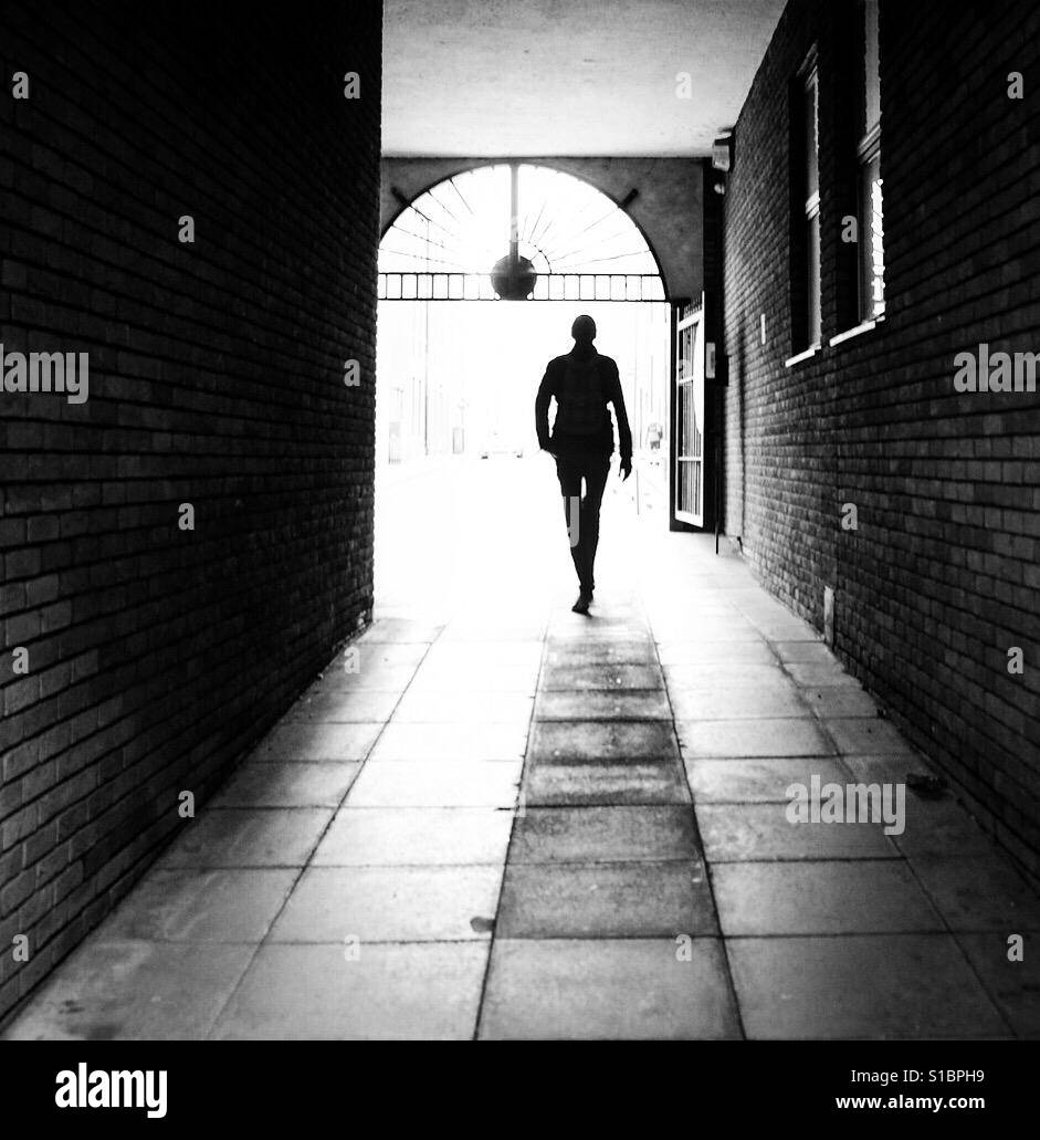 Silhouette di un alto uomo a piedi attraverso un vicolo, Leeds, West Yorkshire. - Immagine stock catturata con smartphone