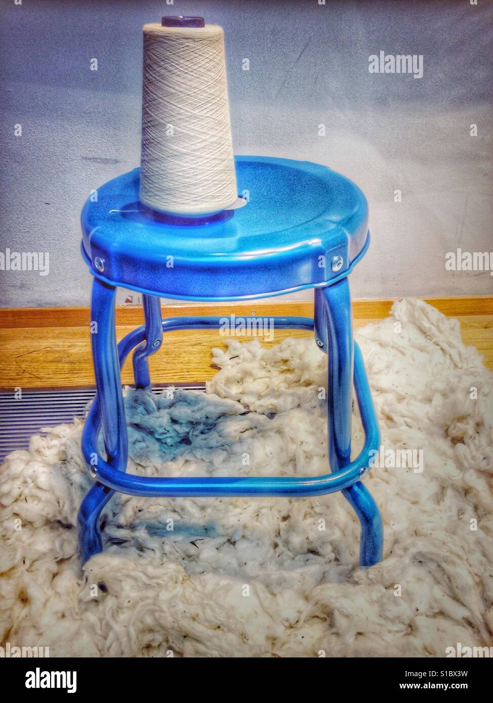 Filo bobina su un sgabello blu e lana di pecora su un pavimento Foto Stock
