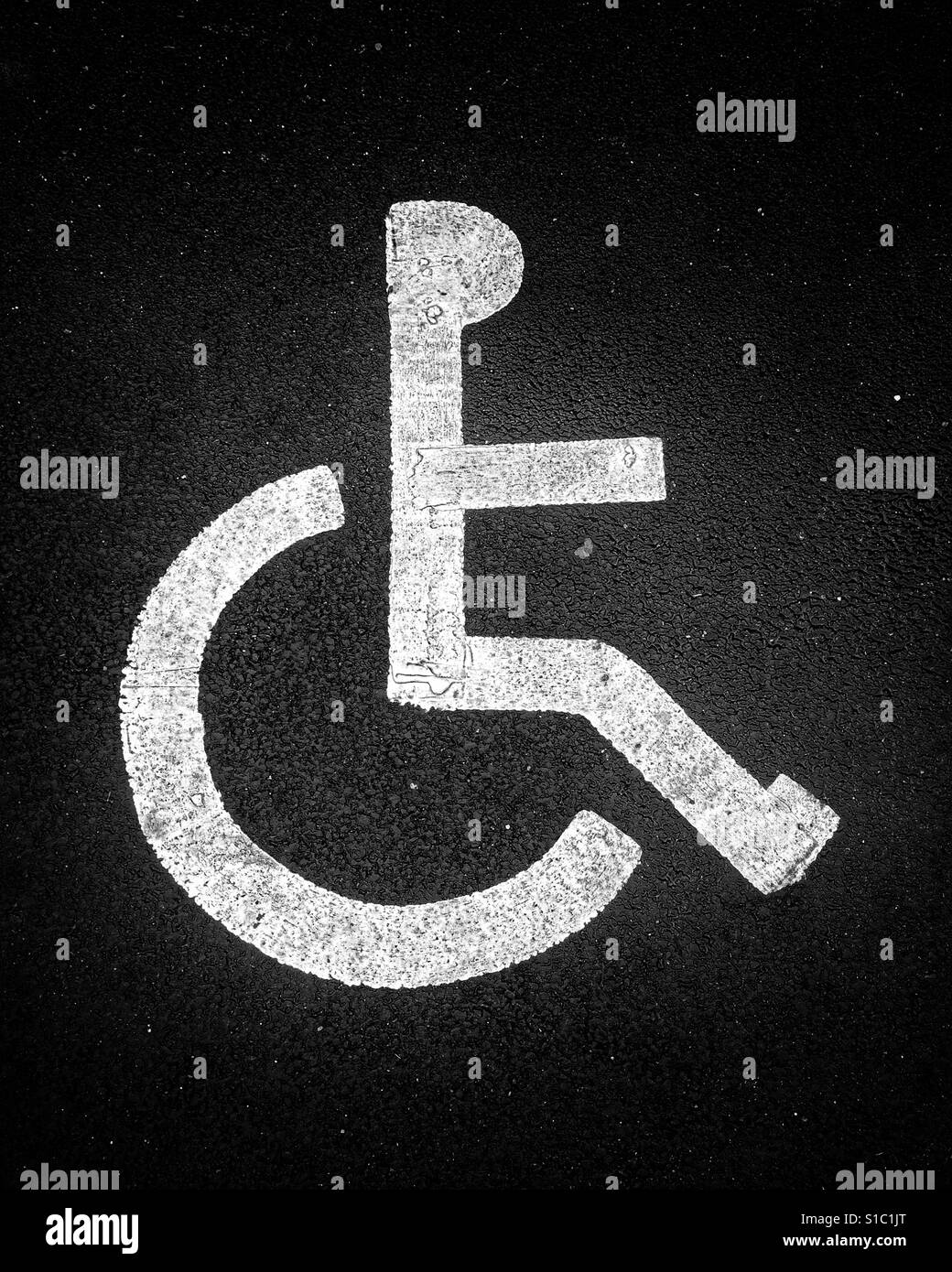 Dipinto di bianco di marcatura su strada segno per un parcheggio disabili bay raffigurante un bastone figura in una sedia a rotelle. Foto Stock