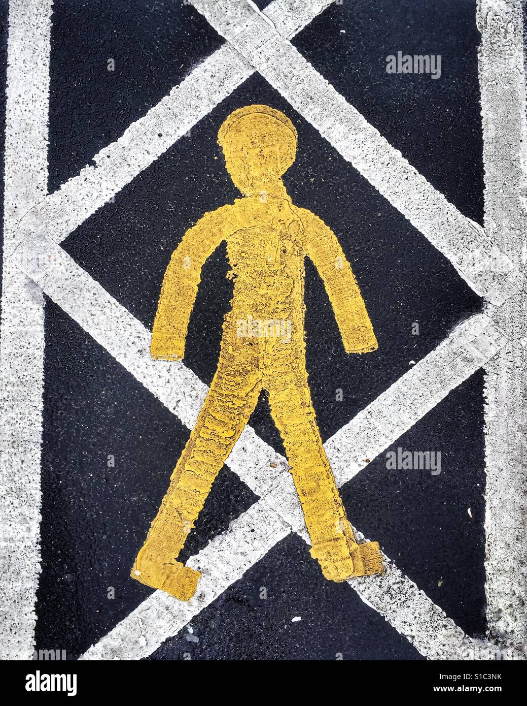 Giallo e bianco verniciato marcatura stradale segno raffigurante il un bastone giallo figura su un sicuro pedonale percorso a piedi. Foto Stock
