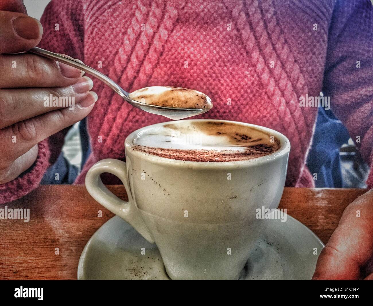 Donna movimenta la schiuma fuori un cappuccino caffè, close up Foto Stock
