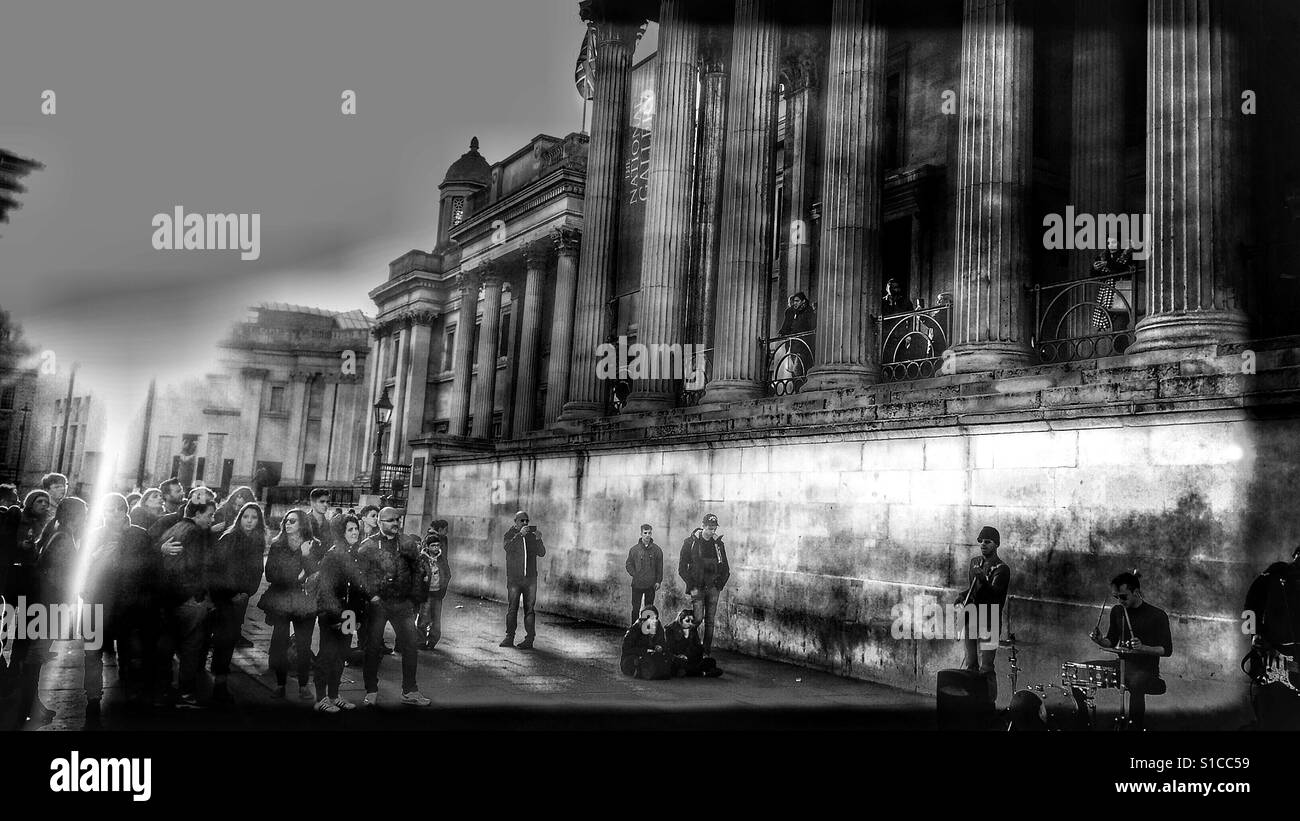 Guardando buskers giocando, Trafalgar Square, Londra Foto Stock