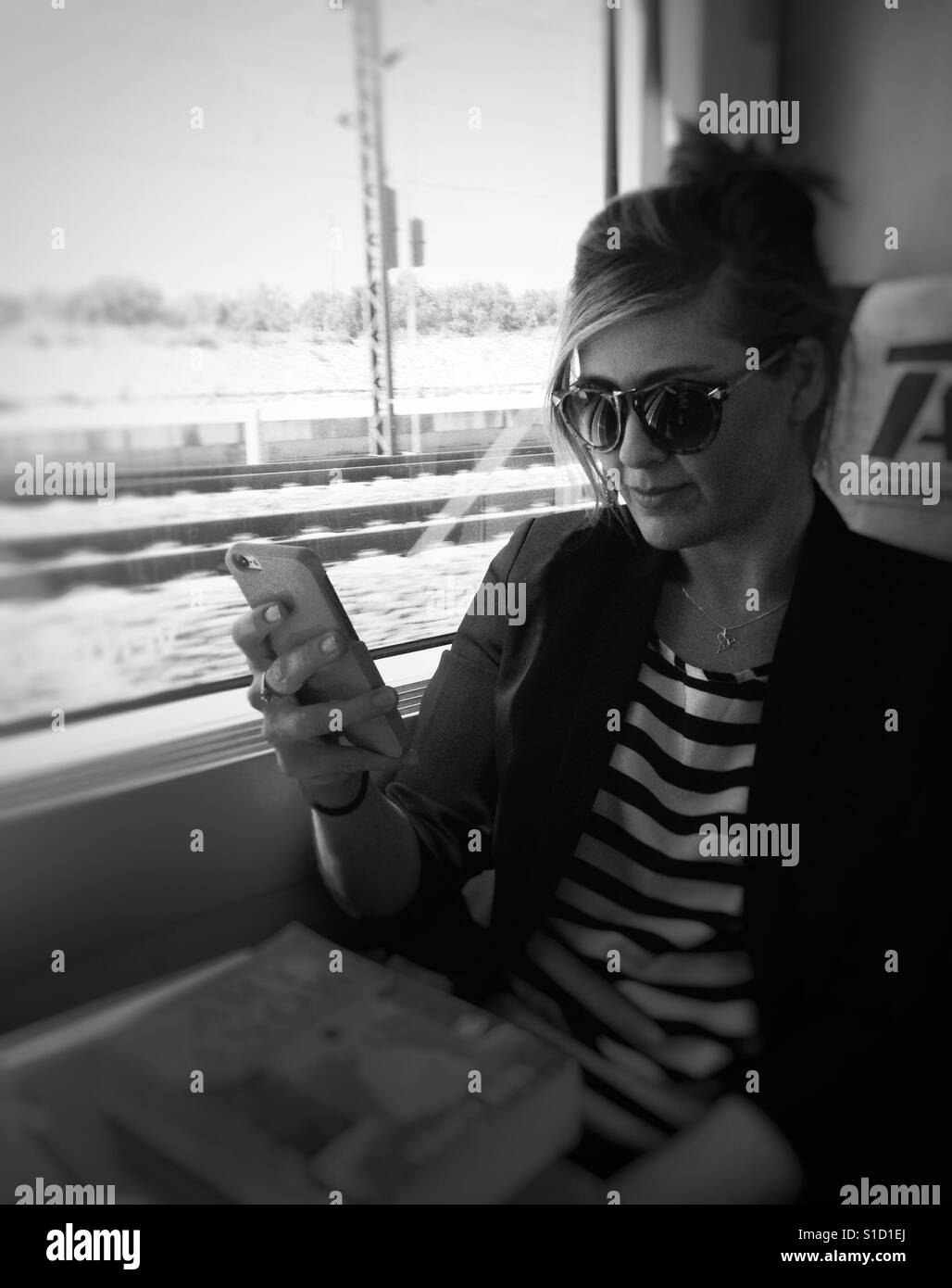 Giovane donna sul treno guardando il suo iPhone Foto Stock