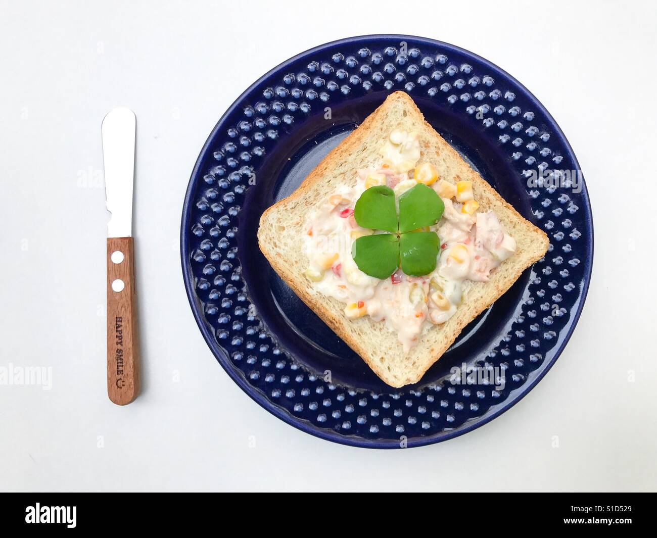 Fette di pane condito con tonno spalmato su una lastra blu e un coltello per burro Foto Stock