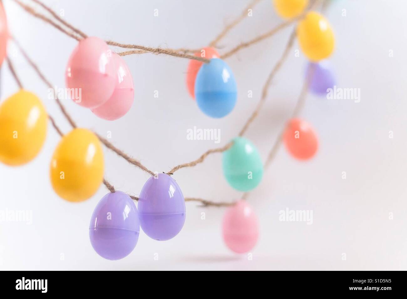 Il Pastel-Color uova di plastica sulla corda di iuta per decorazioni di Pasqua Foto Stock