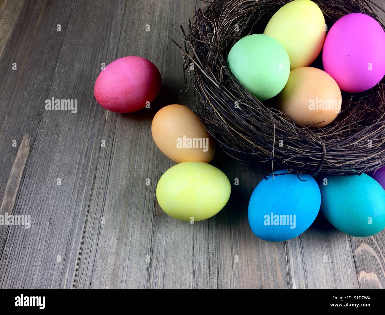 Uova di Pasqua in un nido su una superficie di legno Foto Stock