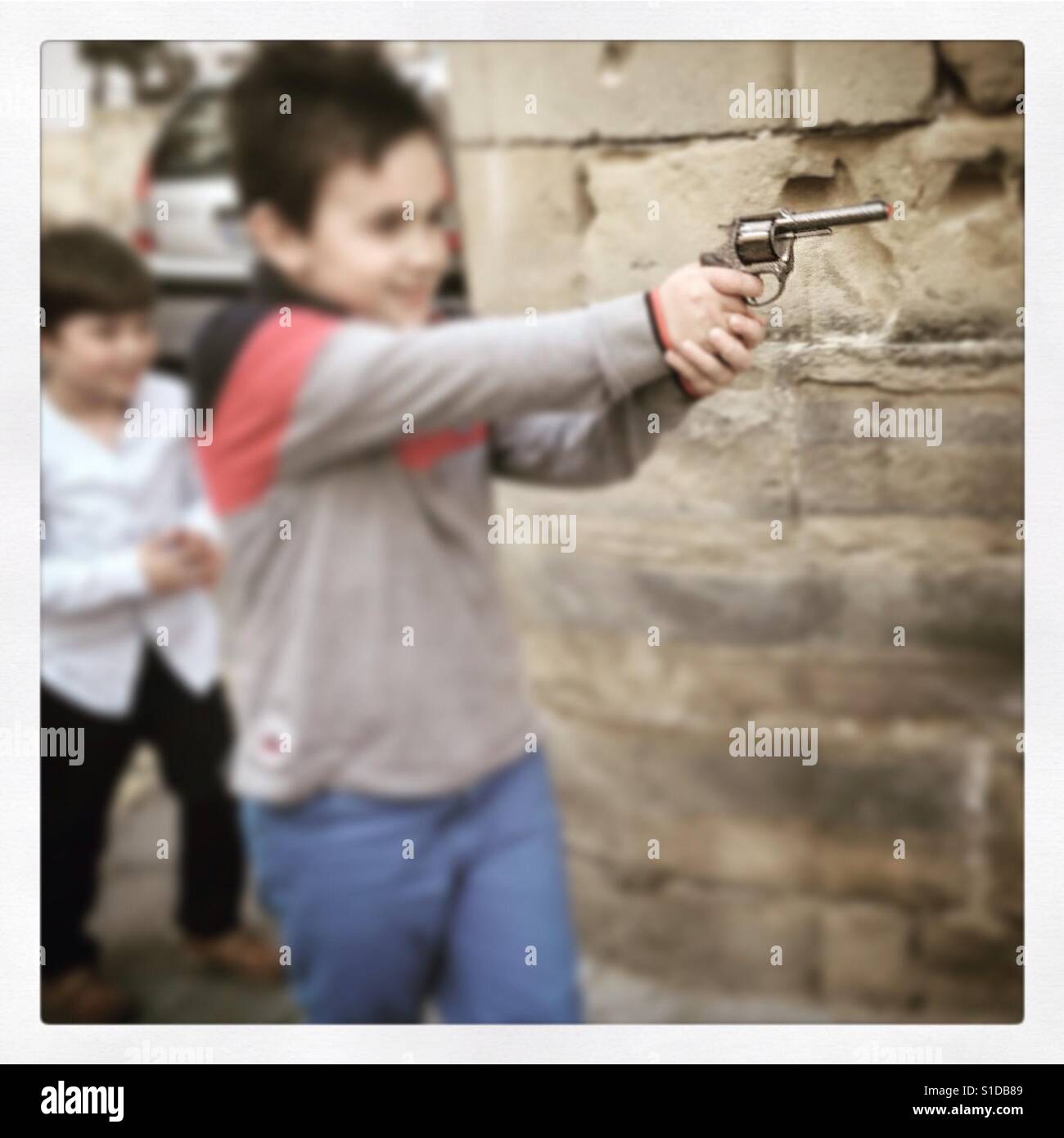 Ragazzo pointd pistola giocattolo come egli finge di sparare i suoi amici in città andalusa Baeza in Spagna meridionale. Foto Stock