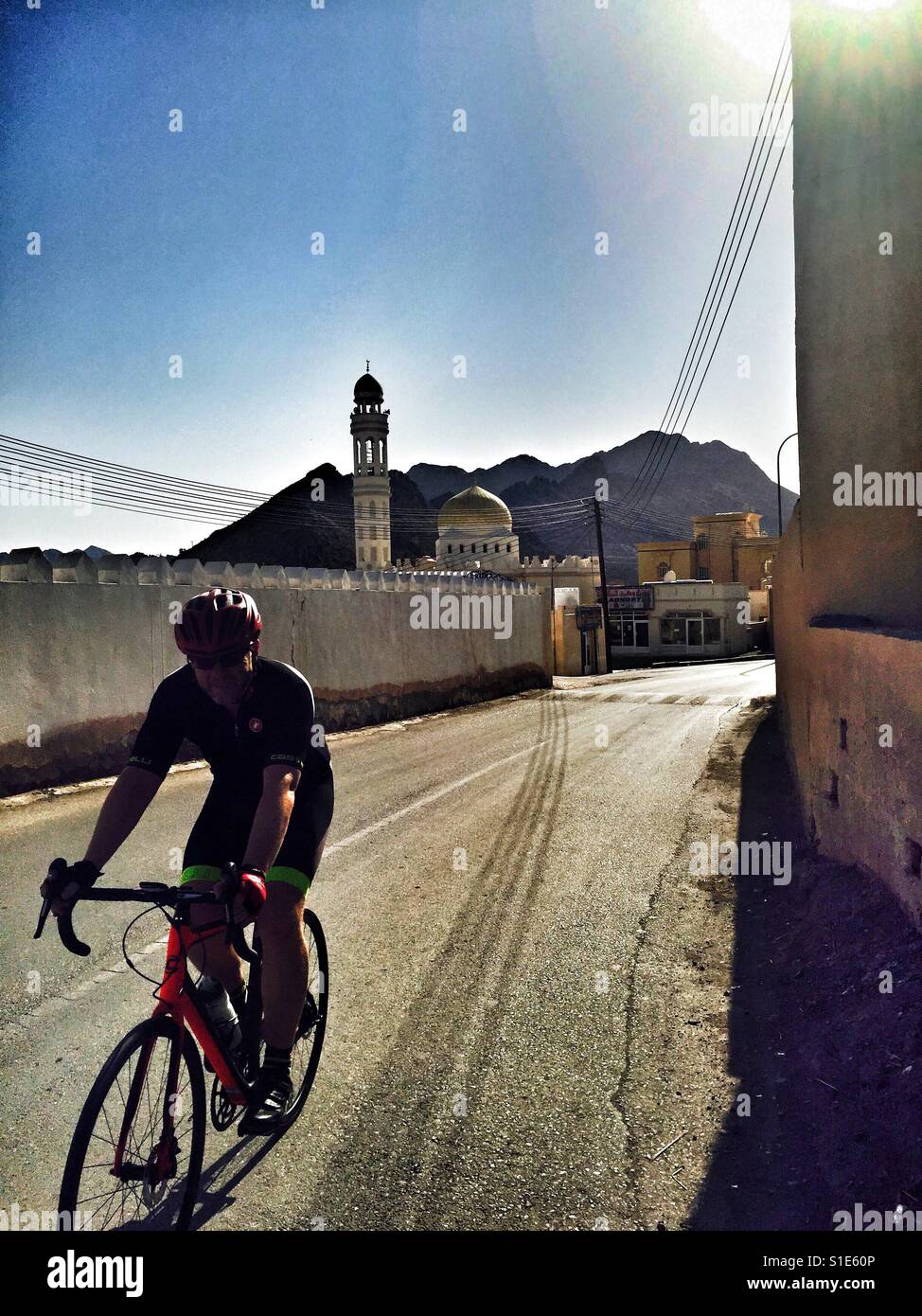 Pedalando attraverso un piccolo villaggio moschea, Fanja, Oman Foto Stock