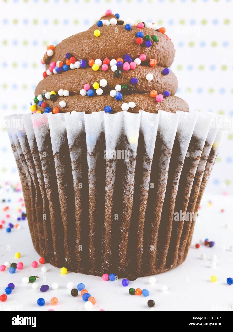 Close up di un cupcake al cioccolato con glassa di cioccolato e caramelle colorate spruzza. - Immagine stock catturata con smartphone