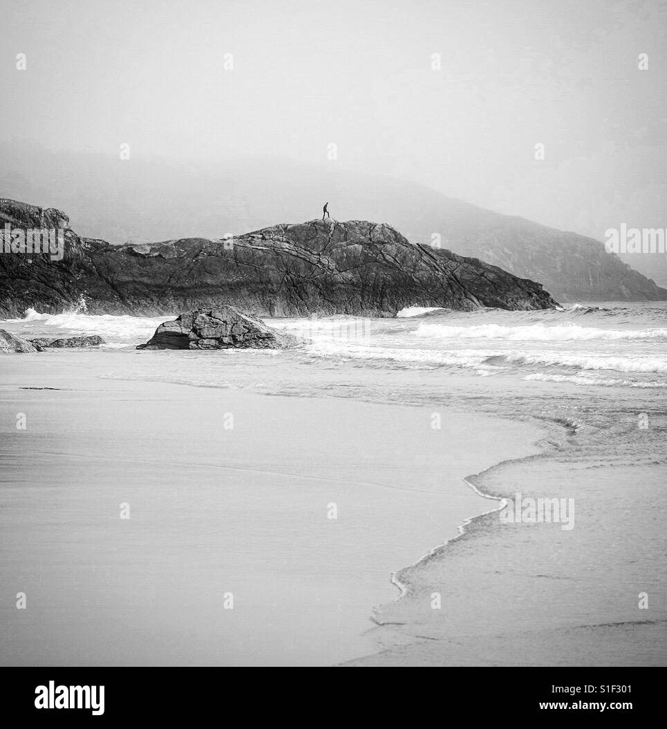 Uomo di arrampicata sulle rocce Durness Beach, Scozia. Foto Stock