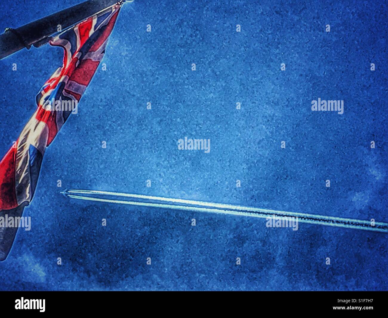 Union Jack flag e aereo con il sentiero di vapore contro il cielo blu - Immagine stock catturata con smartphone