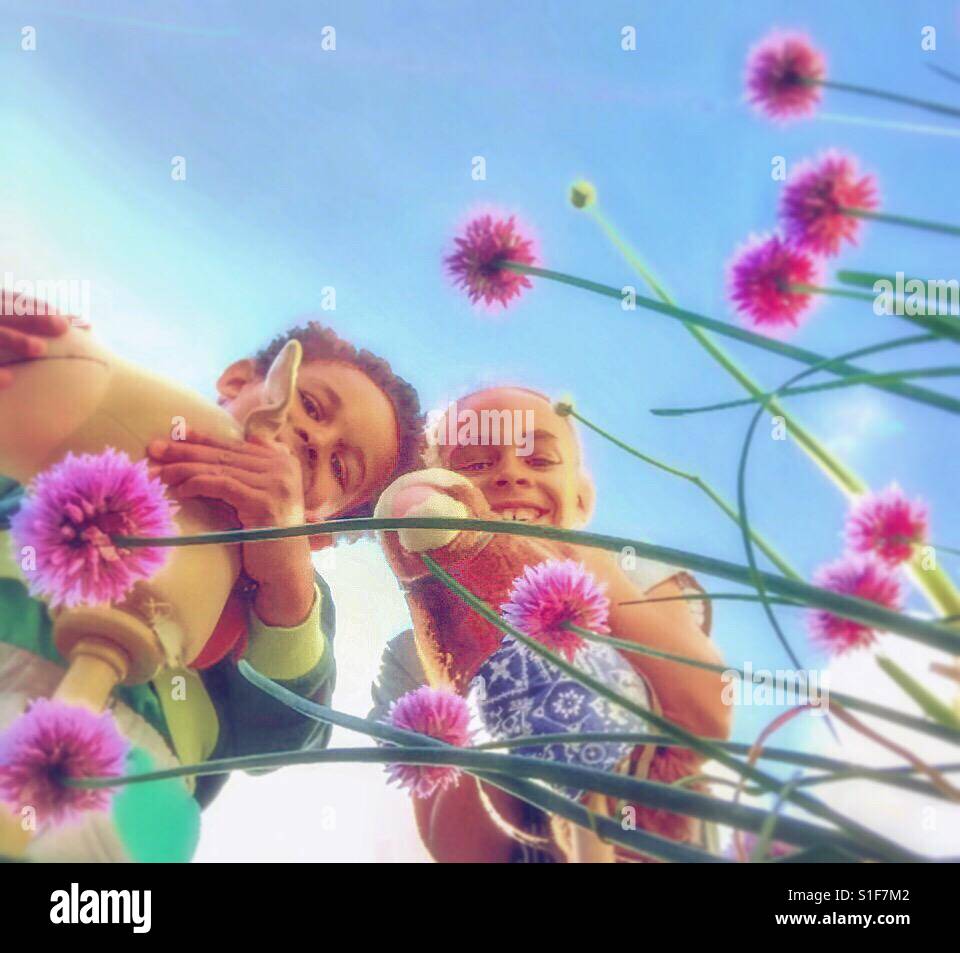 Bambini che giocano in un giardino con fiori di erba cipollina. - Immagine stock catturata con smartphone