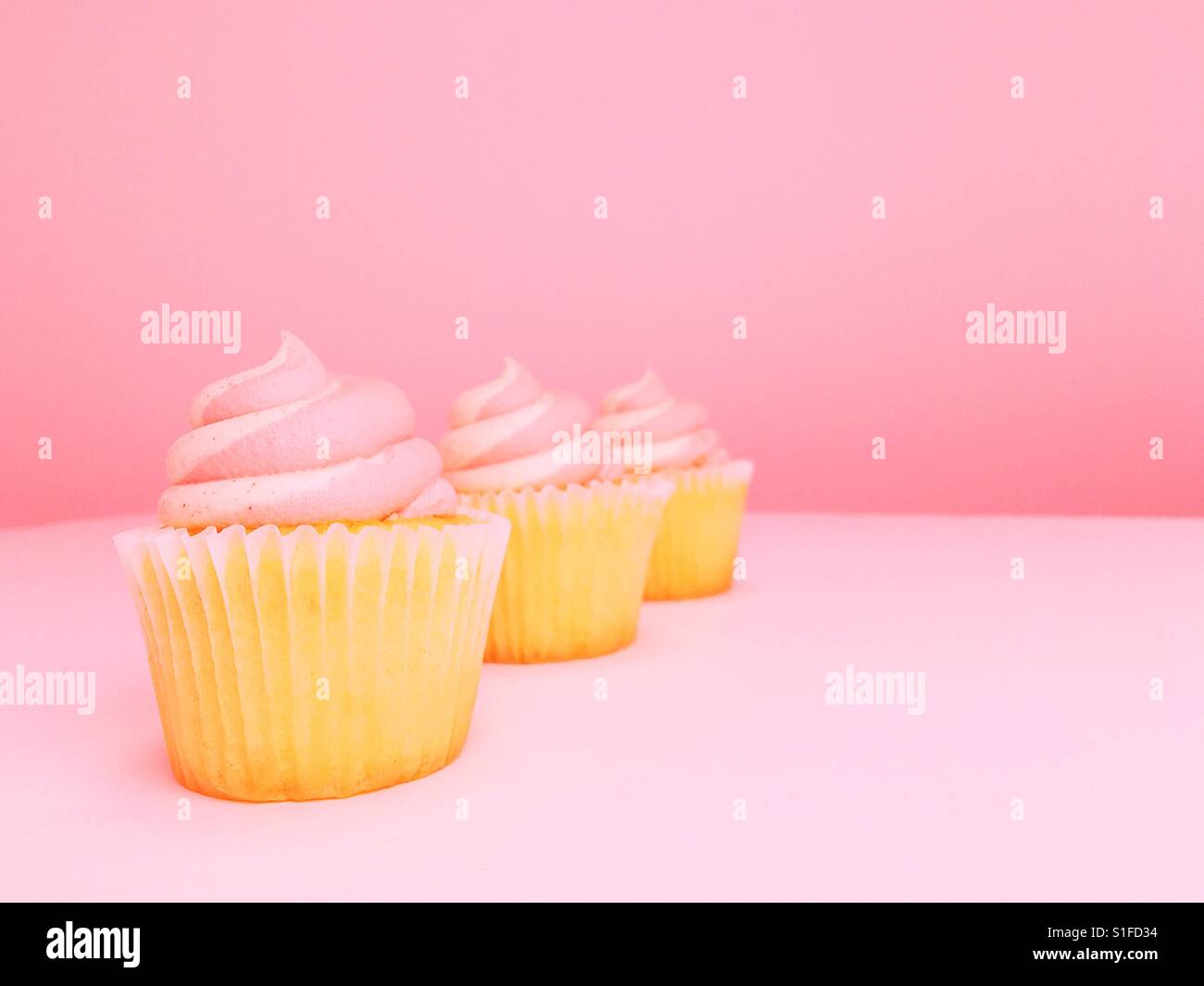 Tre smerigliato tortini di vaniglia su sfondo rosa. Camera per copia. - Immagine stock catturata con smartphone