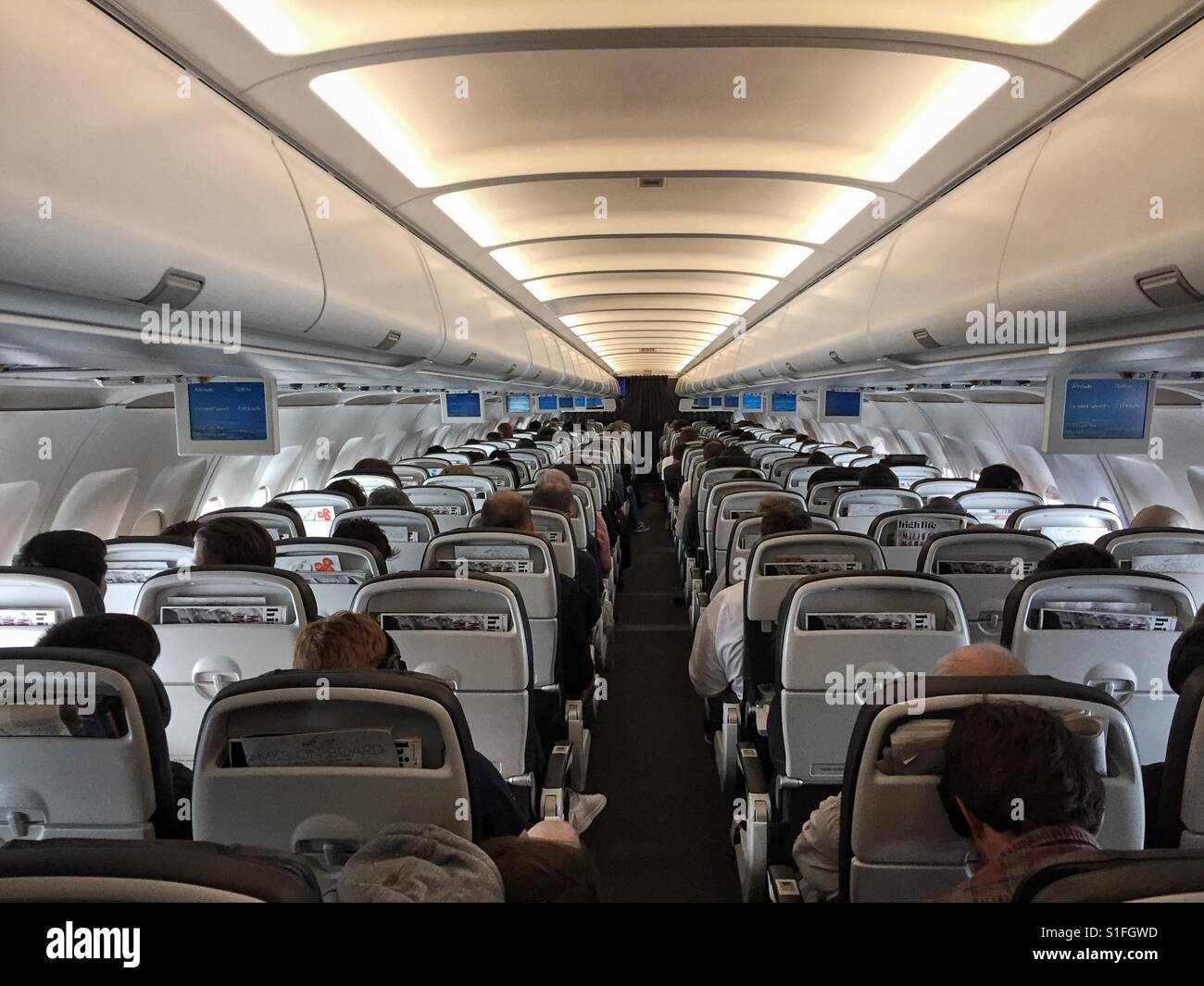 A bordo di un aereo di linea. Vista del corridoio dalla parte posteriore di un aereo di passeggero - Immagine stock catturata con smartphone A bordo di un aereo di linea. Vista del corridoio dalla parte posteriore di un aereo di passeggero - Immagine stock catturata con smartphone