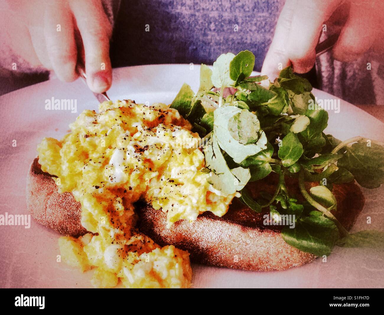 Donna di mangiare uova strapazzate e insalata verde foglie sul pane tostato Foto Stock