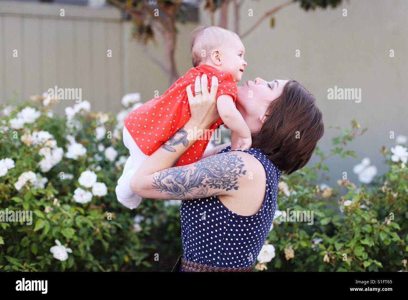 Hip giovane mamma con tatuaggi holding bambina figlia Foto Stock