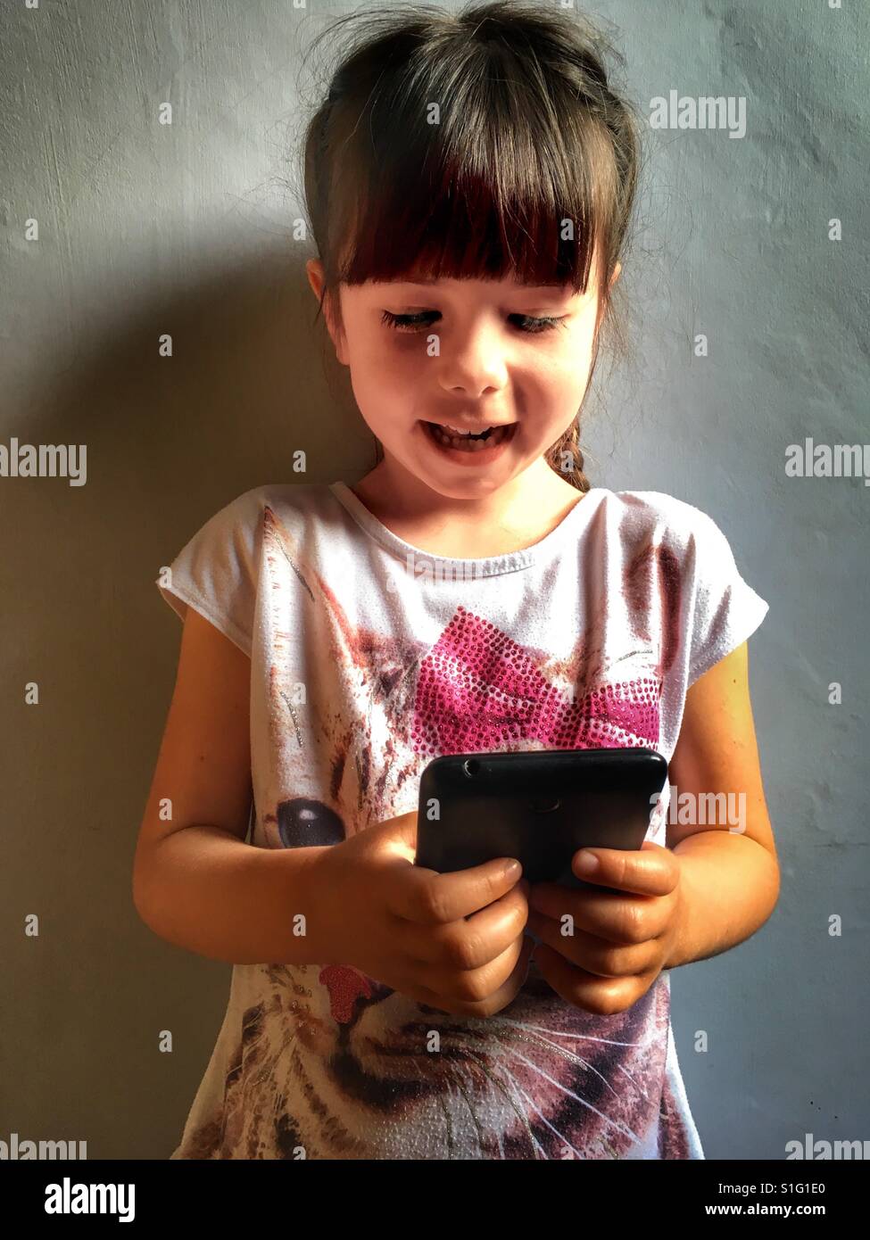 Bambino utilizza lo smartphone - Immagine stock catturata con smartphone