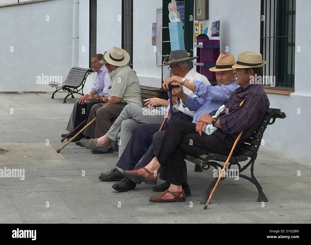Un gruppo di vecchi uomini seduti su una panchina al di fuori di un negozio, in Frigliana, Nerja, Andalusia, Spagna Foto Stock