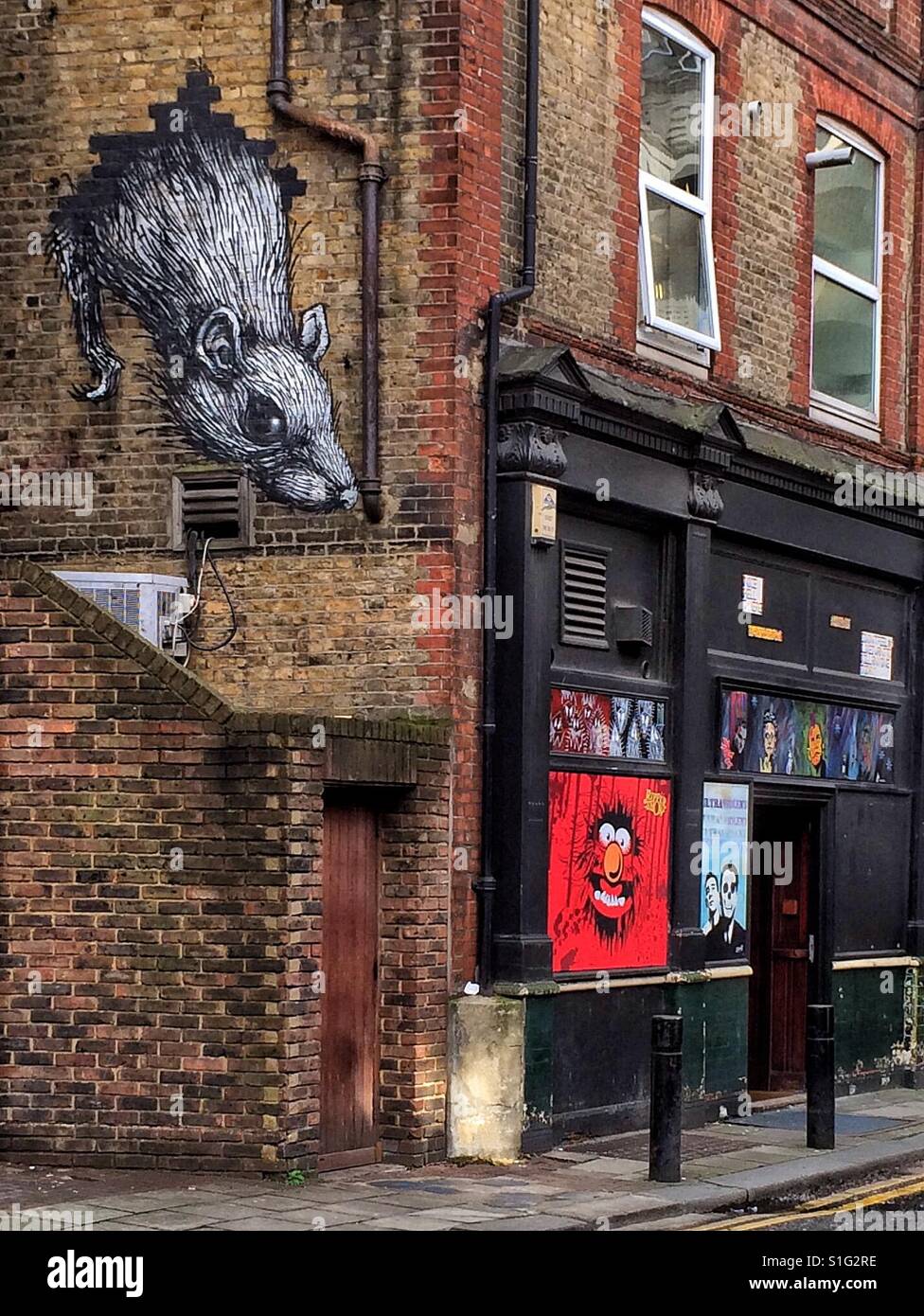 Colorata arte di strada su una parete in mattoni di area di corsia dell'East End di Londra Foto Stock