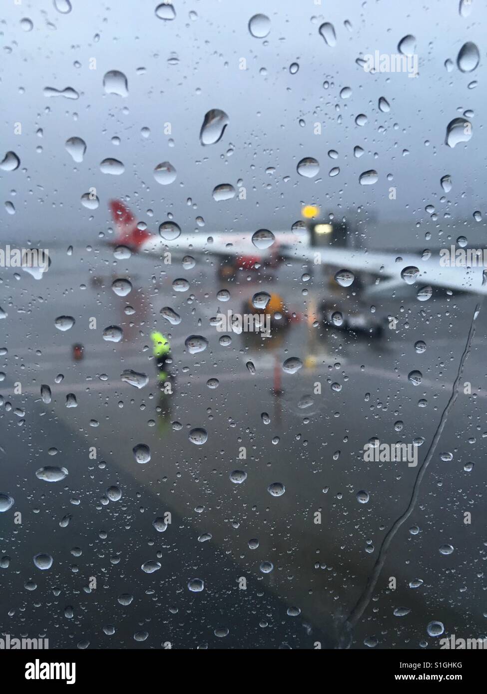 Le gocce di pioggia sul vetro della finestra a Airport Lounge di attesa - Immagine stock catturata con smartphone