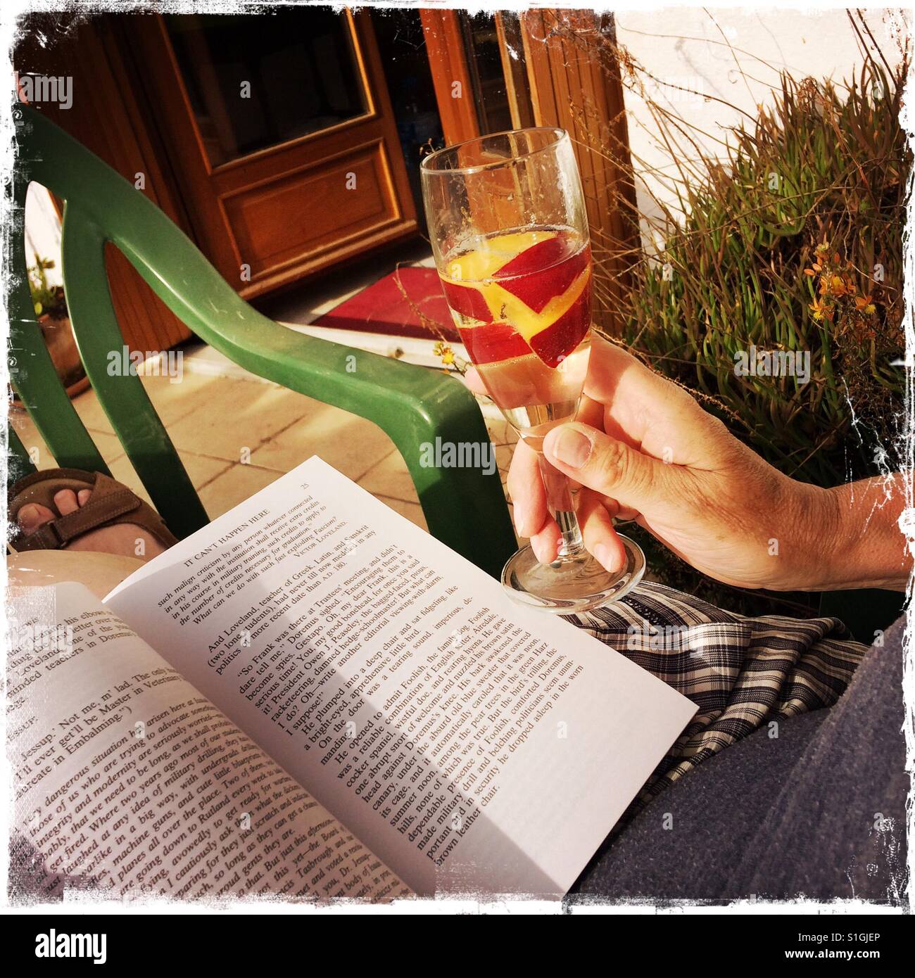 Donna rilassarsi leggendo un libro con un drink al sole. Foto Stock