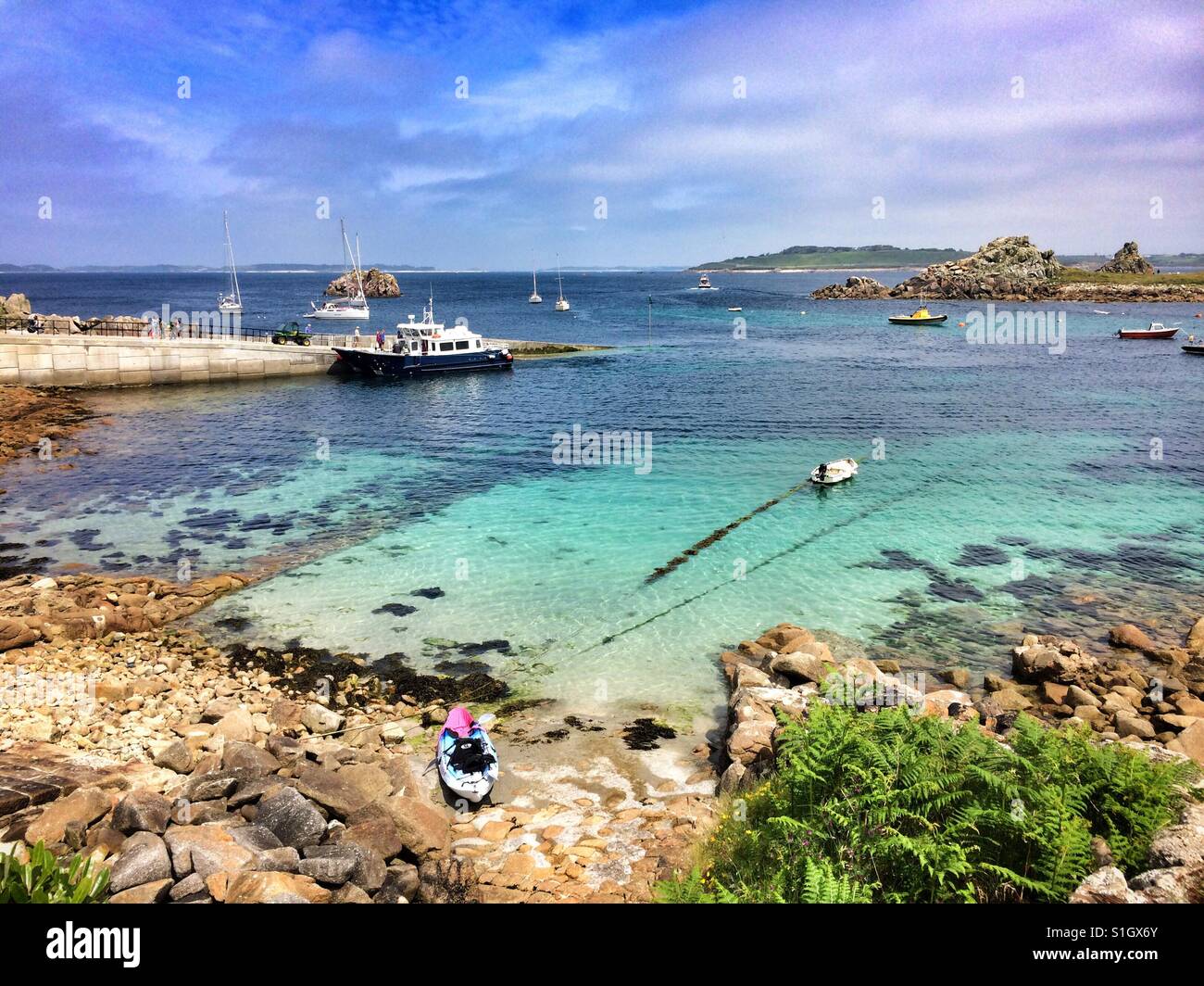 La vista dall'esterno le teste di turco pub sull isola di Sant Agnese, Isole Scilly. La barca "acquavite di Sant Agnese' è legato fino a quey trasferendo i passeggeri e le altre isole sono visibili. - Immagine stock catturata con smartphone