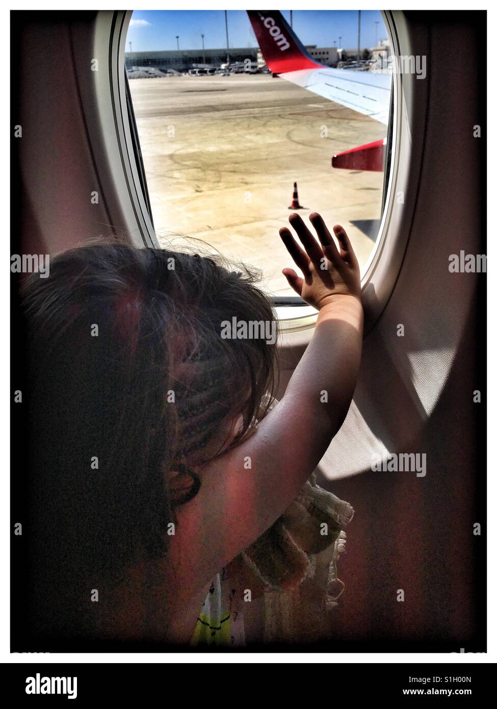 Bambina con la sua mano sulla finestra di aereo. Foto Stock