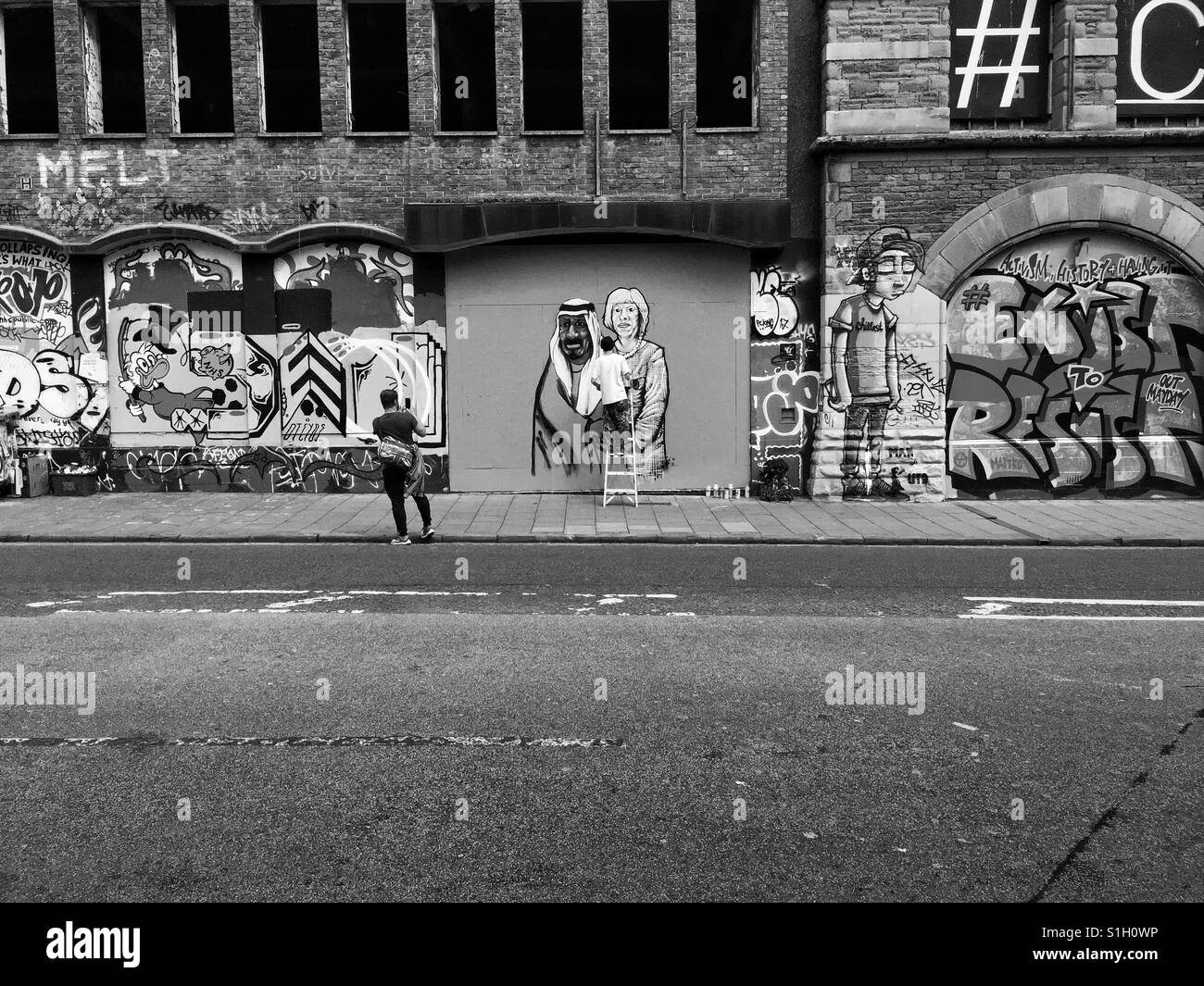 Un passante da fotografie di un artista di strada al lavoro in Stokes Croft, Bristol, Regno Unito Foto Stock