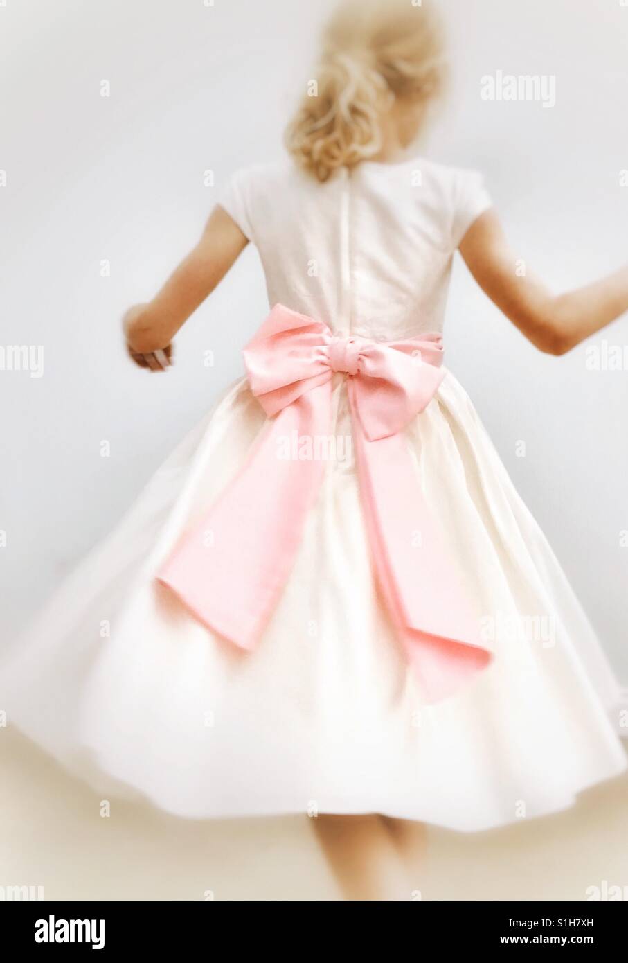 Giovane ragazza fa roteare round in damigelle abito con grande fiocco rosa Foto Stock
