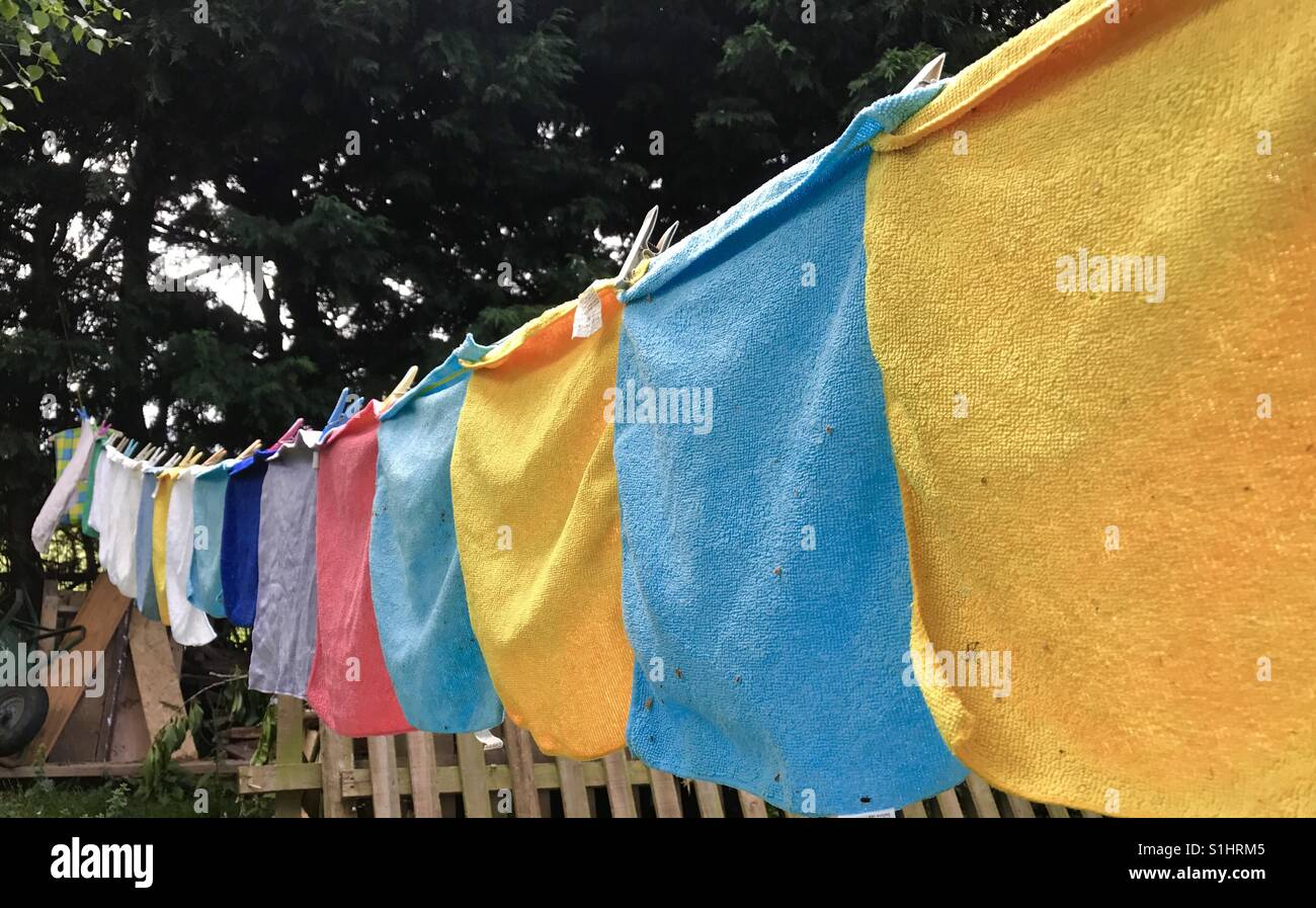 Una linea di lavaggio piena di colorati allegramente strofinacci di essiccazione al sole. Foto Stock