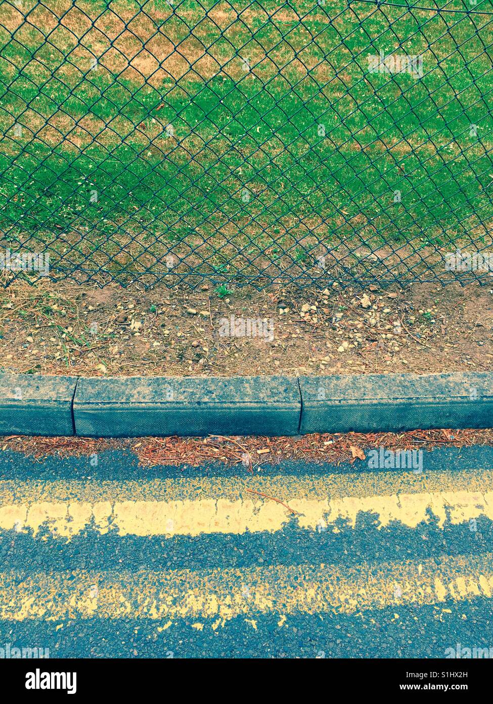 Doppia linea gialla e una recinzione con filo di pollo Foto Stock