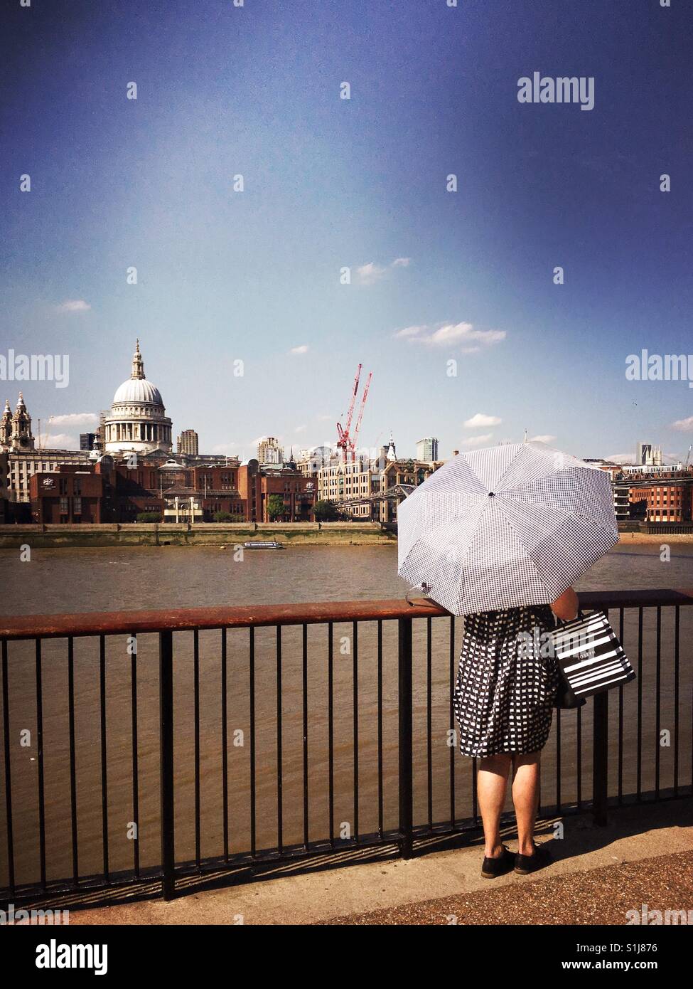 Donna in abito di smart con ombrello come essa si erge contro Londra vista con la cattedrale di St Paul e visibile all'orizzonte. - Immagine stock catturata con smartphone