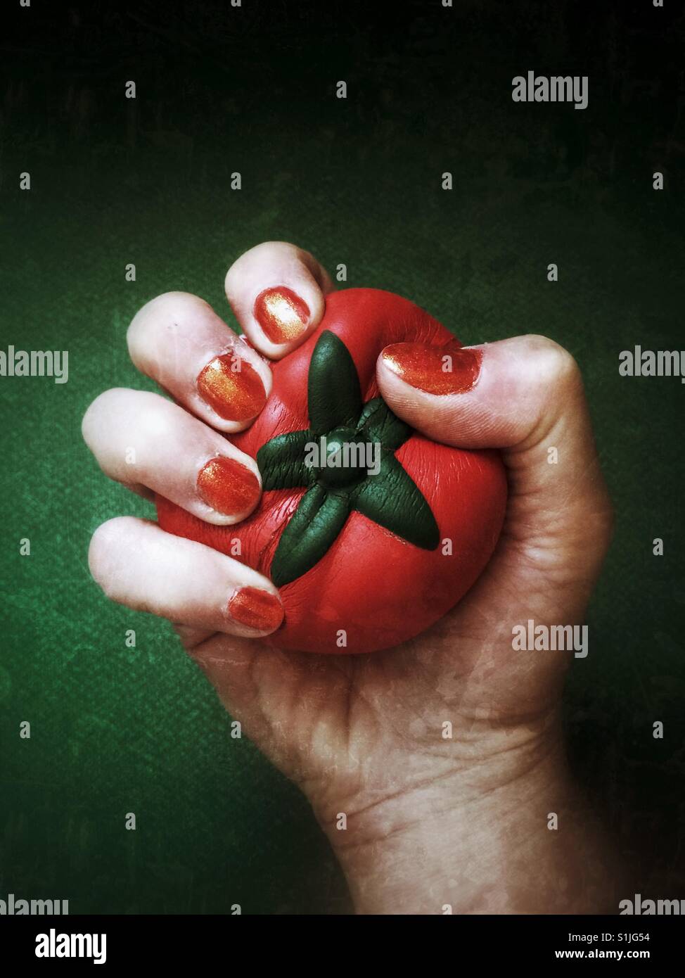 Una donna di spremitura a mano un pomodoro a forma di sfera dello stress Foto Stock