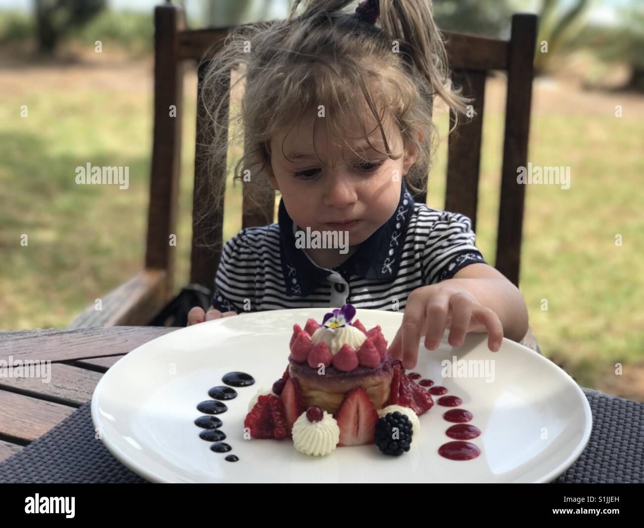 Ragazza guardando il dessert nella piastra su un tavolo - Immagine stock catturata con smartphone