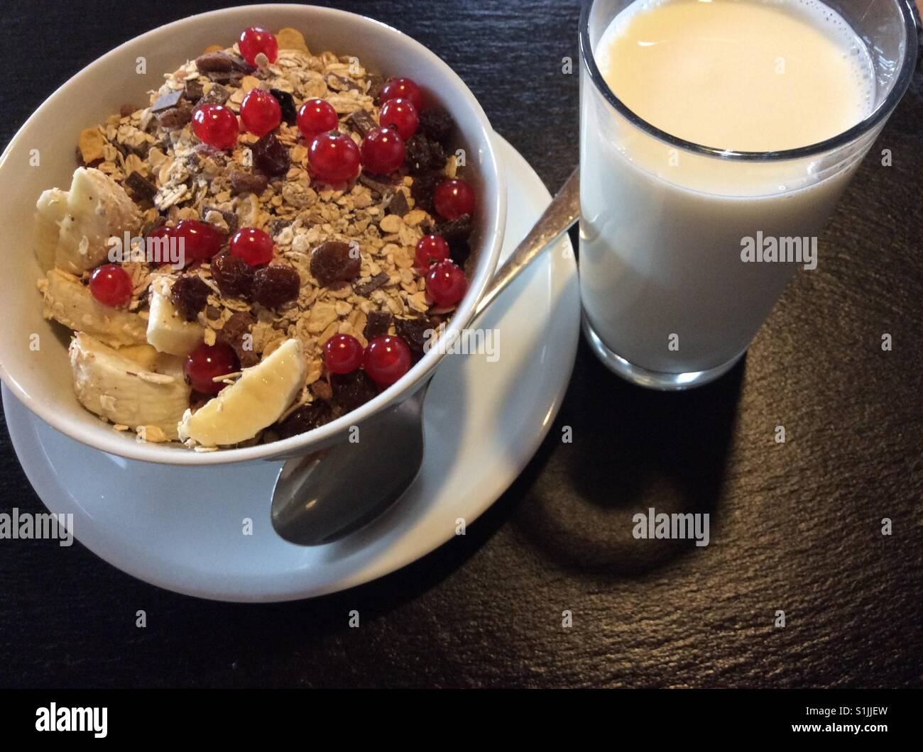 Cereali per la prima colazione, ribes rosso, banana, uvetta e latte Foto Stock