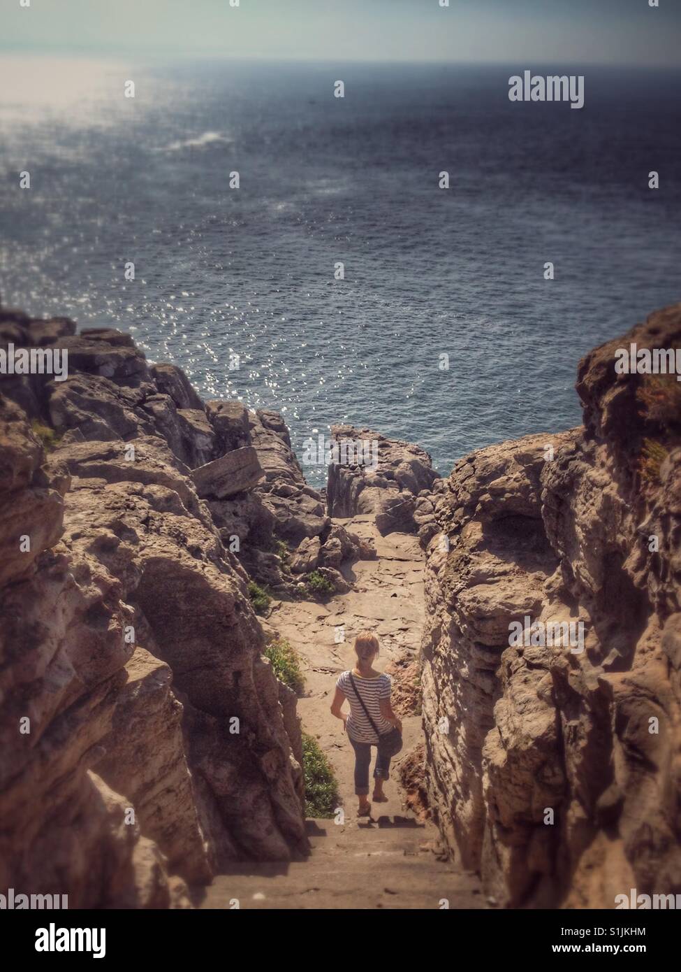 La donna a piedi giù per le scale di fronte vista oceano da scogliere in Peniche, Portogallo . Foto Stock