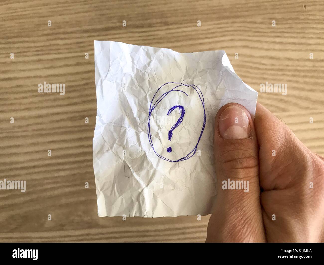 Mano che tiene una carta con un punto interrogativo scritto - Immagine stock catturata con smartphone