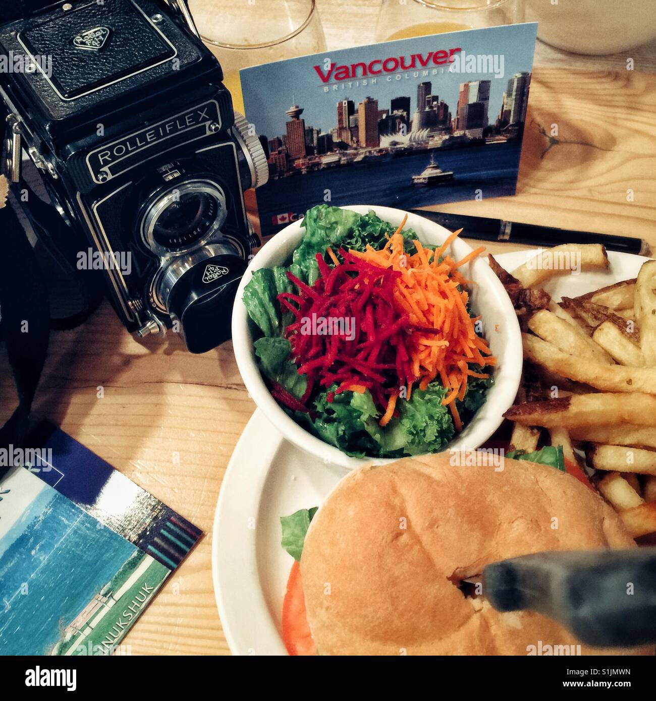 Vivere la vita di tipo analogico nel XXI secolo - cartoline di scrittura mentre mangia vegan burger in Vancouver BC Foto Stock