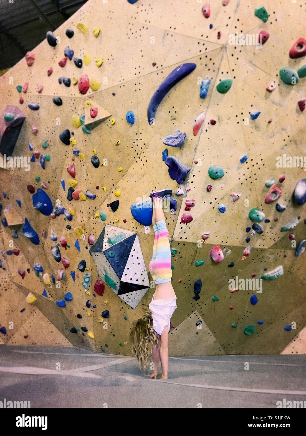Una ragazza esegue un handstand davanti a una piscina parete di arrampicata. - Immagine stock catturata con smartphone