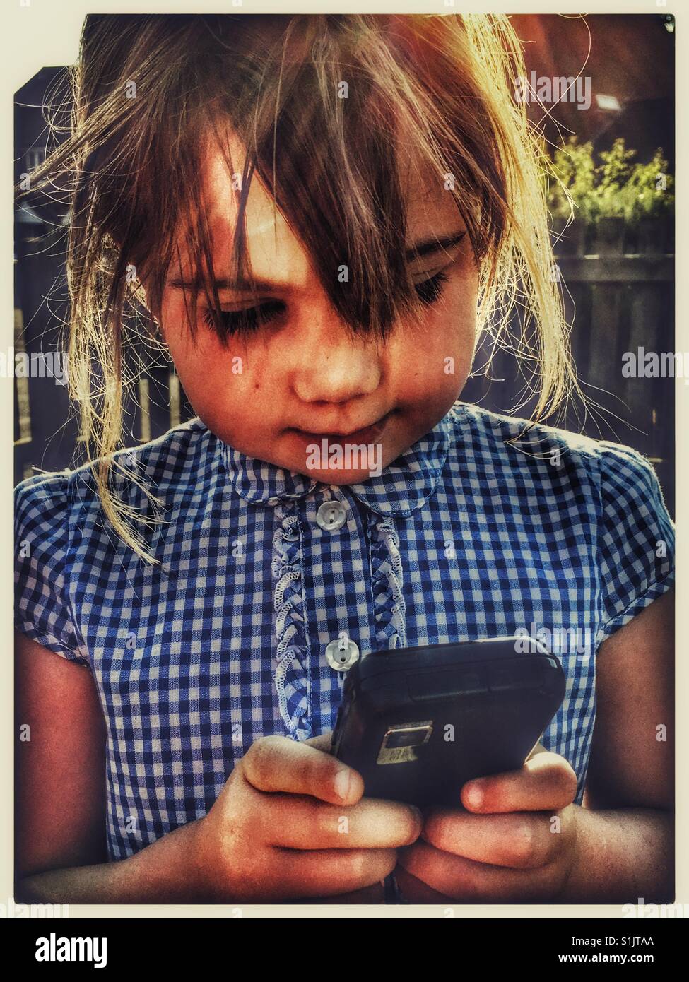Bambina gioca con un telefono cellulare. Foto Stock